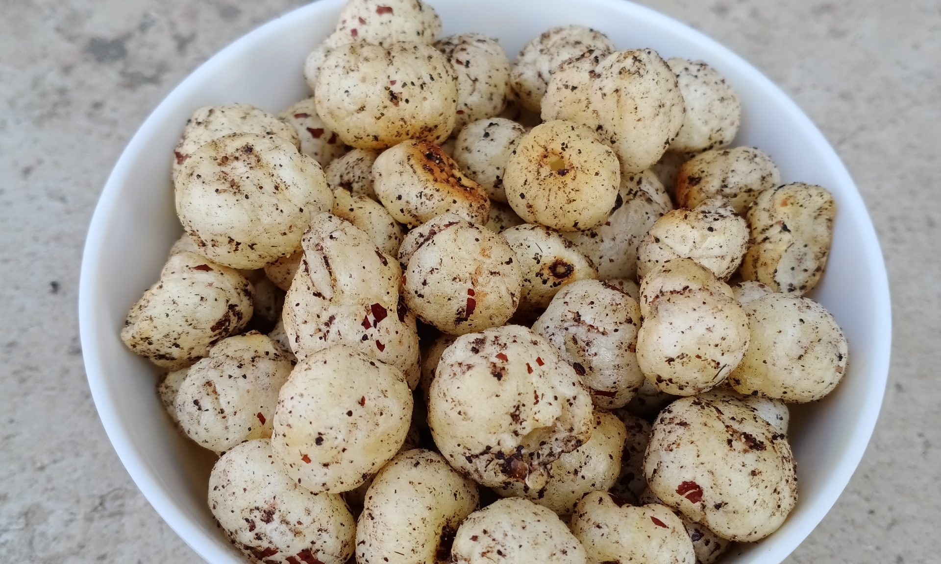 A bowl of masala-roasted makhana with ghee sheen, spice dust and toasted edges